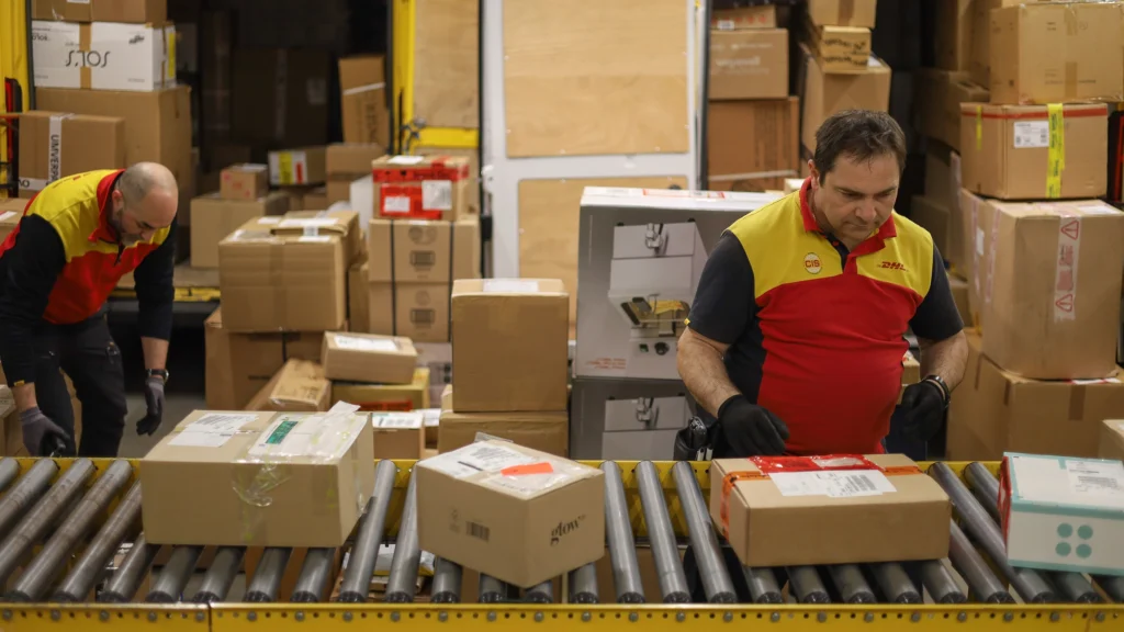 DHL Mitarbeiter sortiert Paket für Auslieferung